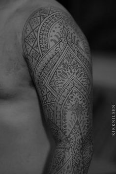 black and white photograph of a man's arm with intricate tattoos on his arms