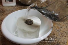 a close up of a toilet paper roll in a sink with water pouring from a faucet