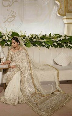 a man and woman sitting next to each other in front of a white couch with flowers on it