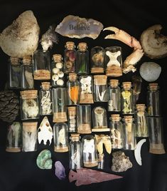 an assortment of items are displayed in glass bottles with corks and shells on them