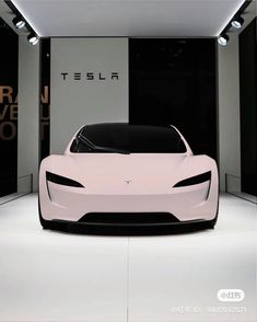 an electric car is shown in front of a wall with the tesla logo on it