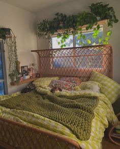 a bed sitting in a bedroom next to a window covered in green blankets and pillows