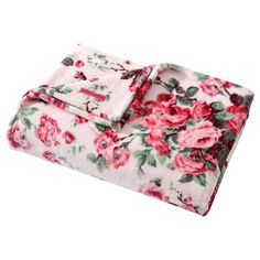 a pink flowered blanket on top of a white surface with red and green flowers