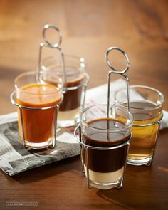 three shot glasses filled with liquid sitting on top of a wooden table next to a napkin