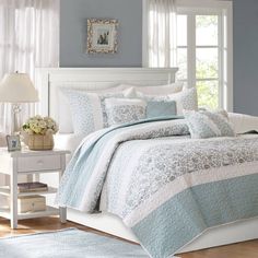 a bed with blue and white comforters in a bedroom next to a window,