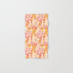 an orange, pink and yellow floral print napkin on a white surface with the corner folded up