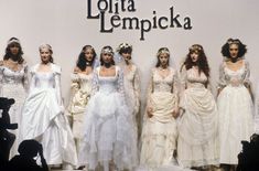 a group of women in white dresses standing next to each other on a stage with the words lolla lempicka written above them