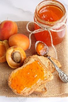 there is a jar of honey, bread and fruit on the table next to it