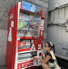 a woman squatting down next to a vending machine