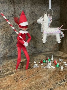 an elf is holding a candy cane and standing next to a dog ornament