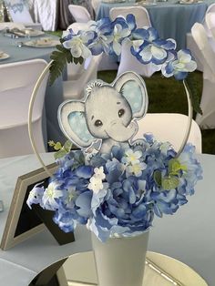 a vase filled with blue flowers and an elephant cut out of it's head