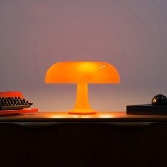 an orange lamp sitting on top of a desk next to a typewriter