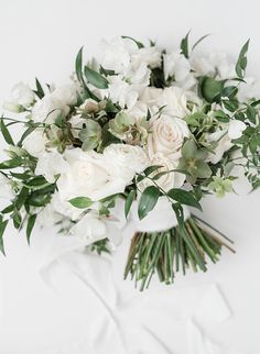 a bridal bouquet with white flowers and greenery