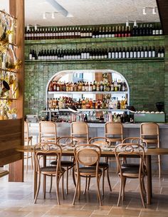 an empty restaurant with many chairs and bottles on the wall