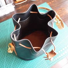 a purse sitting on top of a green cutting board next to a pair of scissors