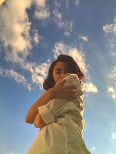 a woman standing under a cloudy blue sky