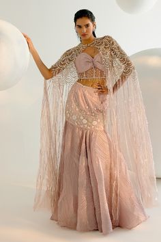 Onion pink cape with crystal embellishment and pearl, sequin, metal chain embroidery. Paired with embroidered padded blouse and attached cancan fishcut lehenga. - Aza Fashions Glamorous Lehenga With Pearl Embroidery For Party, Glamorous Pearl Embroidered Party Lehenga, Glamorous Party Lehenga With Pearl Embroidery, Glamorous Hand Embellished Dupatta For Party, Party Lehenga With Pearl Embroidery, Pink Cape Dress For Wedding, Festive Lehenga With Pearl Embroidery And Cape Sleeves, Pink Organza Lehenga For Evening, Glamorous Pink Lehenga For Party