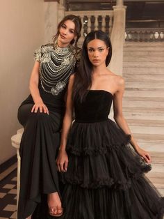 two women in black dresses standing next to each other