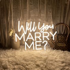 a light up sign that says will you marry me? next to a basket and purse