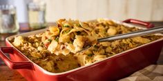 a red casserole dish full of pasta and meat with a spoon in it