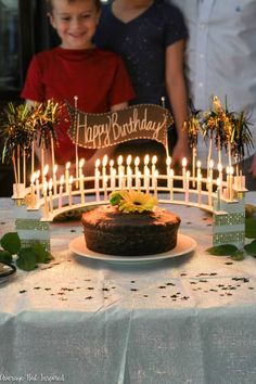 a birthday cake sitting on top of a table with lots of lit candles in front of it