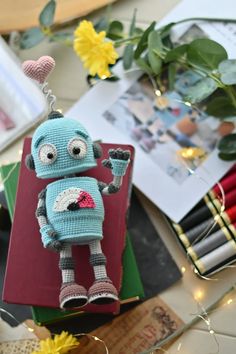 a knitted toy sitting on top of a book next to flowers and other items