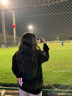 a woman taking a photo of a soccer field at night