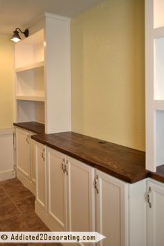 an empty kitchen with white cabinets and wood counter tops