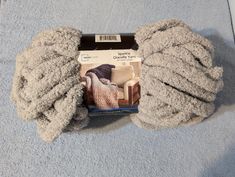 a pair of gray knitted mittens sitting on top of a blue carpeted floor