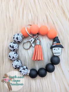 an orange and black bracelet with skulls on it, two charms and a skull keychain