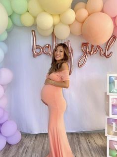 a pregnant woman standing in front of balloons