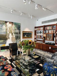 a living room filled with lots of furniture next to a book shelf full of books