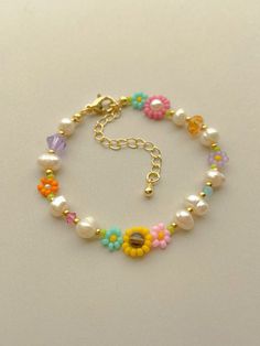 a bracelet with flowers and pearls on it's side, sitting on a white surface