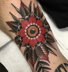 a close up of a person's arm with a flower tattoo on the forearm