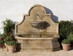 there is a water fountain in the middle of some potted plants