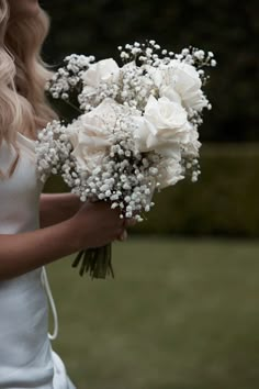 a woman holding a bouquet of white flowers