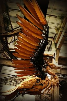 a large bird made out of wooden planks hanging from the side of a building