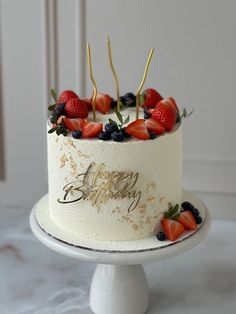 a white cake with strawberries and blueberries on top