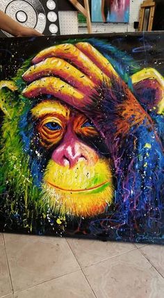 a painting of a monkey with colorful paint on it's face and hands over its head