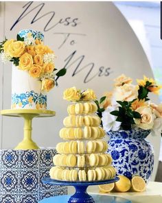 three tiered cakes with yellow flowers and blue vases on the table behind them