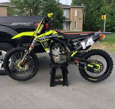 a yellow and black dirt bike sitting on top of a stand in front of a truck