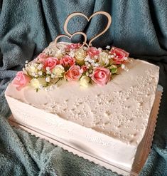 a heart shaped cake with pink and white flowers on top sitting on a blue blanket