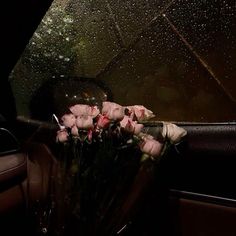 flowers are sitting in the passenger seat of a car with raindrops on it