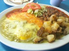 an omelet and some beans are on a white plate with blue table cloth