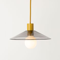 a yellow light hanging from a ceiling fixture with a white wall in the back ground