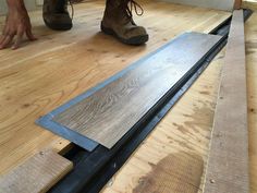 a person standing on top of a hard wood floor next to a piece of plywood