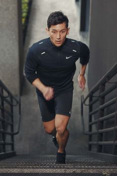 a man is running down the stairs in his black shorts and nike shirt, with one hand on his hip