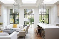 a living room filled with furniture and lots of windows next to a dining table in front of a kitchen