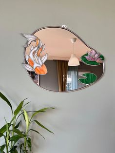 a mirror hanging on the wall above a potted plant