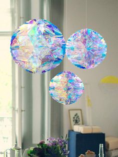 three crystal balls hanging from the ceiling in a living room with blue furniture and windows